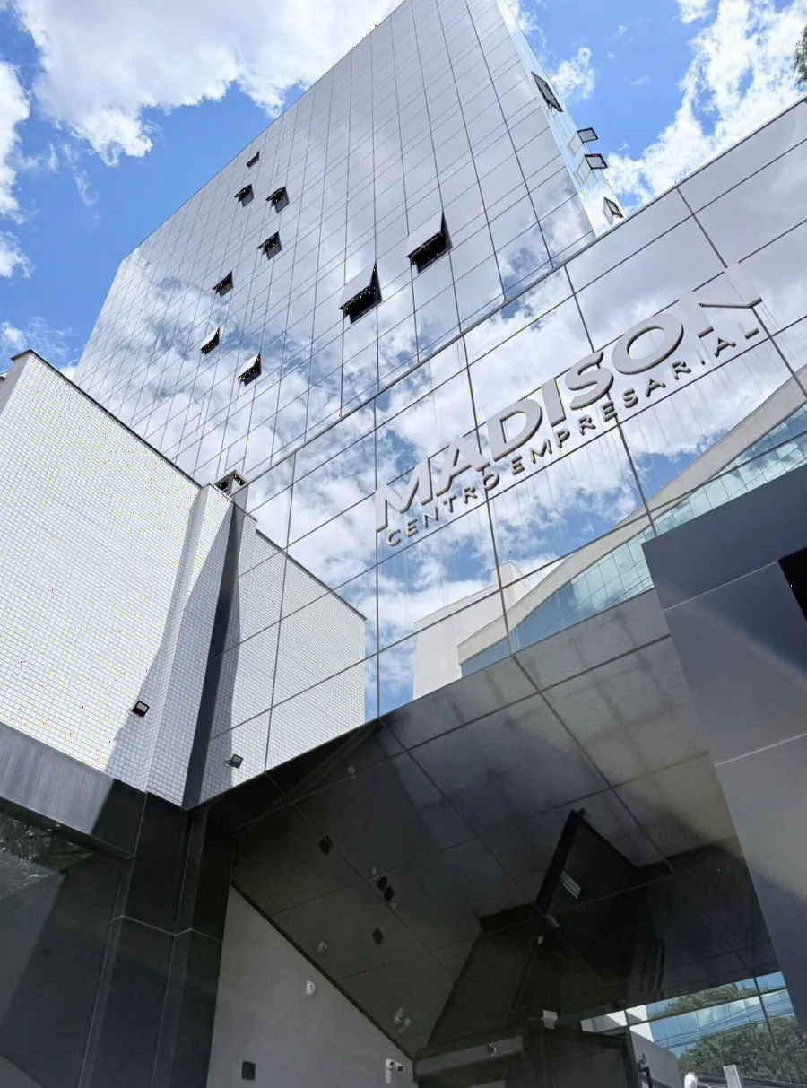 Fachada espelhada do Madison Centro Empresarial, em Maringá, refletindo o céu azul
